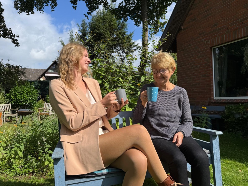Alltagsbegleiterin und Kundin bei einer Tasse Kaffee im Garten